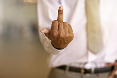Hands, business man and middle finger in office for corporate anger, frustrated and work injustice. Space, rude employee and gesture at workplace for rebellion, company conflict and opinionの写真素材