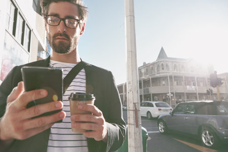 Coffee, commute and phone with business man in city to search for directions to work location. Drink, mobile map and walking with employee person outdoor for travel or trip to urban destinationの写真素材