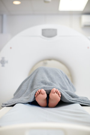 Assessment, healthcare and MRI with feet of patient in machine for appointment or checkup. CT scan, diagnosis and medical equipment with person in hospital for brain anatomy, exam or functionの写真素材