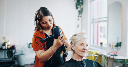 Blow dry, curling and style with people at hairdresser for appointment, consulting or treatment. Brush, hairdryer or service with mature client and stylist in salon for maintenance or restorationの写真素材