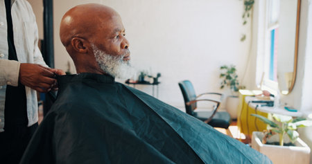 Man, hands and client in barber shop with cape for grooming service, makeover or styling appointment. People, senior customer or consultation in salon with cover, start and getting ready for haircut.の写真素材