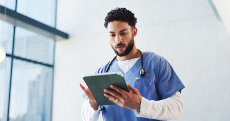 Hospital, doctor and man on tablet in lobby for patient results, medical report and research. Healthcare, professional and person on digital tech for consulting, surgery schedule and help in clinicの写真素材
