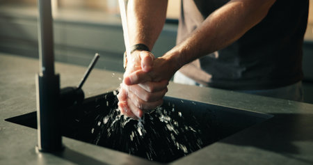 Water, person and washing hands in kitchen for cleaning skin, health or wellness for morning routine. Rinse, tap and man in home for hygiene, germ prevention and self care for bacteria safetyの写真素材