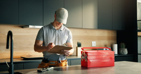Man, technician and writing on clipboard at house for inspection, plumbing evaluation or report. Male person, toolbox and checklist for home maintenance, diagnostic notes and service costs of repairsの写真素材