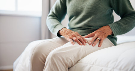 Senior woman, hands and legs with pain on bed for joint ache, arthritis or orthopedic injury in...