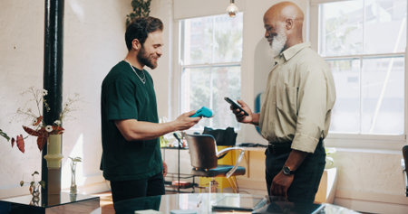 Men, hairdresser or customer with pos machine or phone for payment, banking or checkout in salon. Male people, barber or client with mobile smartphone for tap to pay or wireless transaction in parlorの写真素材