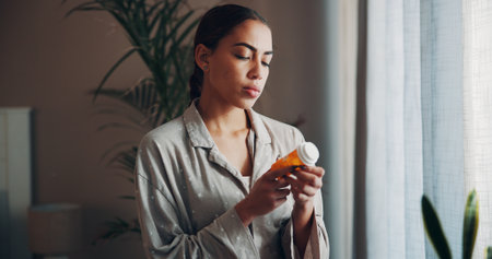 Home, woman and check pills label in morning for prescription, side effects and dosage info. Apartment, person and reading medication instructions for health benefits, ingredients and tablets warningの写真素材