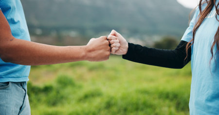Volunteer, hands or fist bump in grass field for ngo event, conservation management or green...