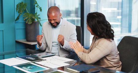 Happy, business people and documents with fist pump for winning, promotion or success in office. Excited, businessman and woman with paperwork or tablet for corporate deal or good news in workplaceの写真素材