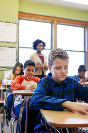 Writing, exam and children with teacher, classroom and boy with academic growth, quiz and knowledge....