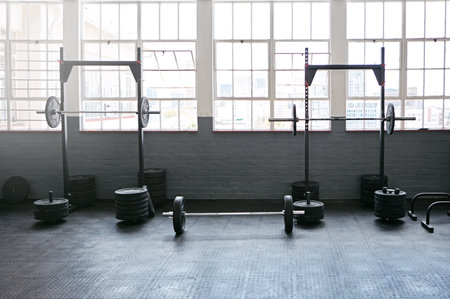 Fitness, barbell and weights in empty gym for bodybuilding training, exercise and cardio workout in studio. Sports, mockup and weightlifting equipment for wellness, strength and strong musclesの写真素材
