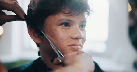 Hand, hairdresser and scissor with child at salon for haircut, remove split ends and grooming. Person, tools or kid for fresh trim, hair maintenance and comb, cutting technique and haircare treatmentの写真素材