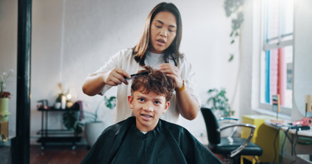 Cutting, hairdresser and child with cape, woman and hair maintenance with equipment. Consultation, appointment and person with boy for haircut, grooming and process with confidence and teenagerの写真素材