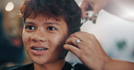Hands, kid and service at hair salon for haircut, grooming or texture maintenance with flare. Teen, boy and trim hairstyle with hairdresser in small business with barbershop tools, comb or scissorsの写真素材