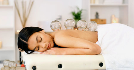 Woman, sleeping or massage with cupping therapy for healing or muscle tension in beauty spa. Calm,...