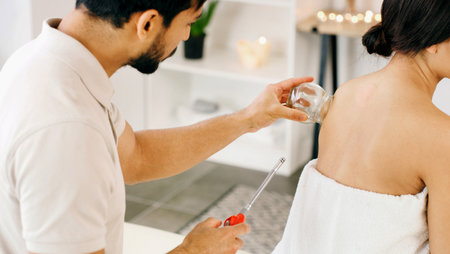 People, glass and cupping therapy for back pain, health and healing for muscle blood flow benefits. Therapist, holistic spa and woman with man for wellness, relax or resort with deep tissue massageの写真素材