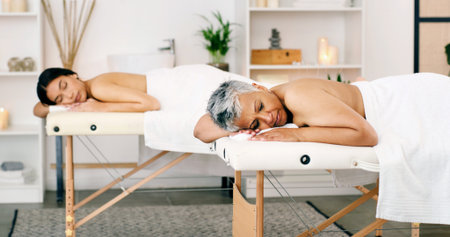 Women, relax or sleeping with massage bed in spa for luxury body treatment, healing or zen in salon. Female people, asleep or holiday getaway together with comfort for beauty therapy or relaxationの写真素材