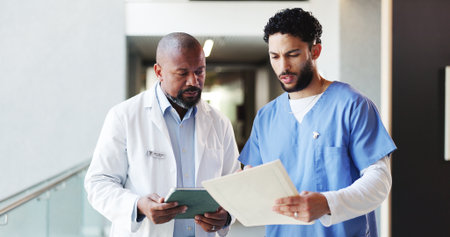 Doctor, tablet or nurse with medical folder in clinic for patient results, health opinion or advice. Healthcare team, men or document in hospital hallway for treatment options, feedback or discussionの写真素材
