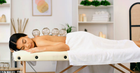 Woman, healing or massage with cupping therapy for muscle tension or comfort in beauty spa. Calm, female person or relax with suction cups for stress relief, relaxation or Chinese medicine in salonの写真素材