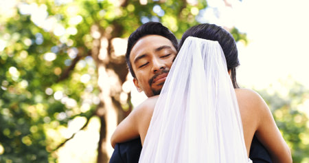 Wedding, couple and smile with hug in nature for marriage celebration, love commitment and loyalty. Happy people, bride and groom with embrace at ceremony for relationship union, connection and bokehの写真素材