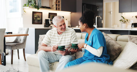 Coffee, healthcare or visit with nurse and old man on sofa in living room of home together....