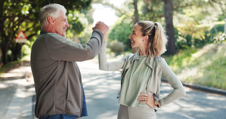 Senior man, personal trainer and fitness with success in road for achievement, workout or exercise. Elderly, male person or coach with smile, handshake or high five for winning or physical activityの写真素材