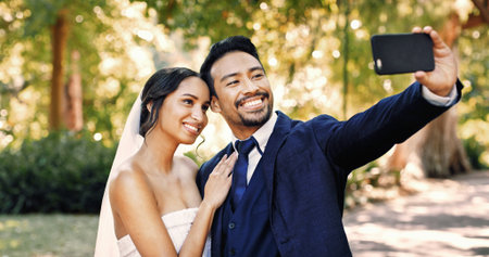 Wedding, couple and selfie at park with smile for special memory, love and post for marriage. Man, woman and picture of bride with groom outdoor for social media profile, romance and celebrationの写真素材