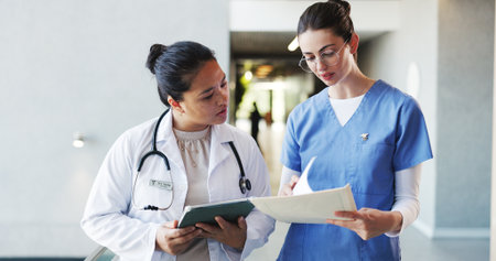 Team, doctor and nurse with report, hospital and discussion for treatment plan, online and paperwork. Clinic, healthcare workers and women with tablet for diagnosis, talk and reading medical recordsの写真素材