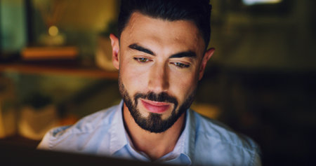 Computer, man and reading in office at night for article review, proofreading and fact checking. Editor, employee and tech at publishing agency for editing deadline, quality control and publicationの写真素材