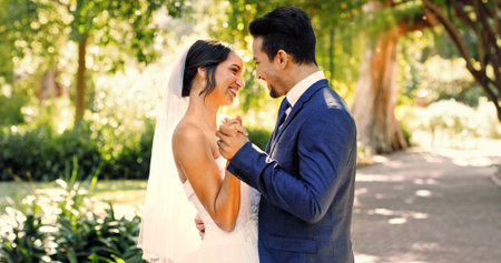 Wedding, happy couple and love in nature with smile, support and celebration for bridal union or marriage. Bride, groom and people in park with dance for life partner, commitment or together outdoorの写真素材