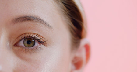 Closeup, eye and woman in studio for optometry, glaucoma or astigmatism exam for vision. Mockup, portrait and female person on pink background with retina, eyesight test or wellness in ocular care.の写真素材