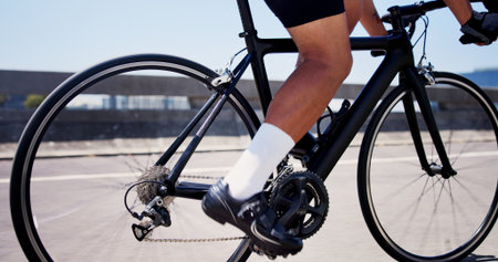 Legs, cycling and bike on bridge for exercise, cardio workout and outdoor on road with speed in town. Person, bicycle and feet on pedals, triathlon training or challenge for fitness in urban cityの写真素材