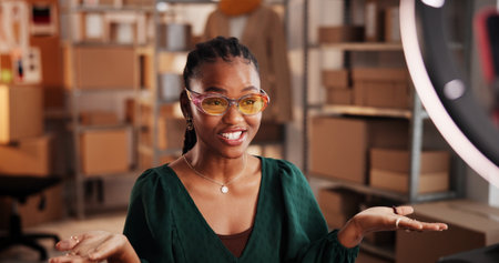 Sunglasses, live stream and advertising with black woman in warehouse for startup promotion and ecommerce. Content creation, online shopping broadcast and influencer with person and accessoryの写真素材
