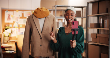 Black woman, live streaming and fashion startup with phone for brand awareness. African person, connection and entrepreneur with ecommerce promotion, advertising clothes on social media and broadcastの写真素材