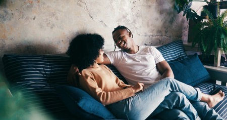 Home, smile and couple on sofa, love and bonding together with comfort, talking and romance. Laughing, happy man and woman on couch, relax or relationship with discussion, humor or trust with breakの写真素材