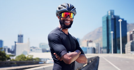 Crossed arms, sports and man in city with sunglasses for fitness, cycling and active hobby outdoor. Athlete, town and person with polarized lens with confidence for exercise, workout and trainingの写真素材