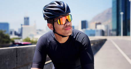 Thinking, sports and man outdoor with sunglasses for fitness, cycling and active hobby in city. Athlete, helmet and person with polarized lens, thoughtful and rest for exercise, workout and trainingの写真素材