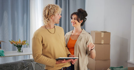 Couple, tablet and smile with boxes in new home for bonding, interior design and layout app in...