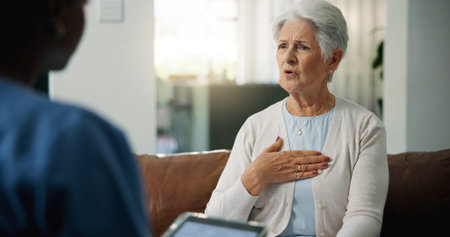 Chest, consulting or medical with old woman and nurse on sofa for help or home appointment....