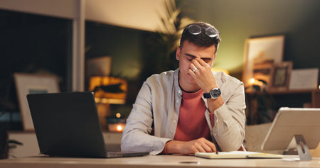 Night, headache or man in office with laptop, screen fatigue or eye strain in task management. Migraine, glasses or employee in workplace with tech, deadline issue or vision discomfort in late shift.の写真素材