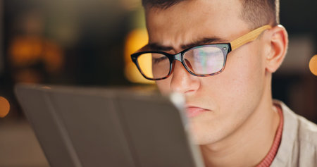 Night, tablet and man with glasses, confused and online reading for web development. Evening,...