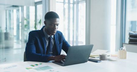 Business, laptop and typing with black man in office for review of corporate or financial data....