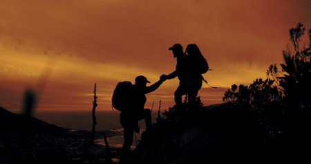 Climbing, help and hiking with silhouette of people outdoor in mountains at sunset for fitness or...