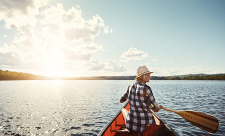 Woman, lake and and portrait with canoeing for vacation with summer adventure, weekend trip and relax. Water sports, kayak and person with paddle for rowing with holiday, outdoor hobby and sunshineの写真素材