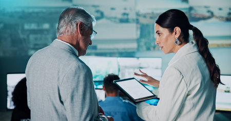 People, security and talking with tablet in control room for surveillance, cctv footage and alert. Mature man, woman and digital for satellite update, monitor worldwide or mockup space for protectionの写真素材