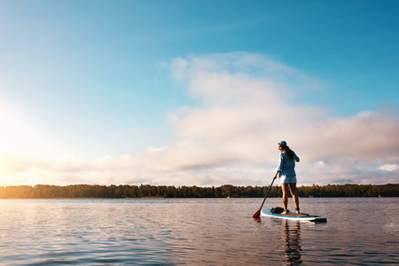Woman, paddle board and view at lake on vacation, tourism or rowing for adventure in summer. Person,...
