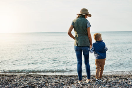 Back, holding hands and mother with son at beach for bonding, summer vacation and connection....