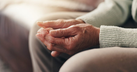 Faith, hands and praying with senior person on sofa in living room of home for belief in God. Holy,...
