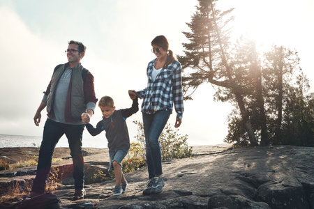 Hiking, parents and holding hands with child, bonding and people with son on holiday, happy and...