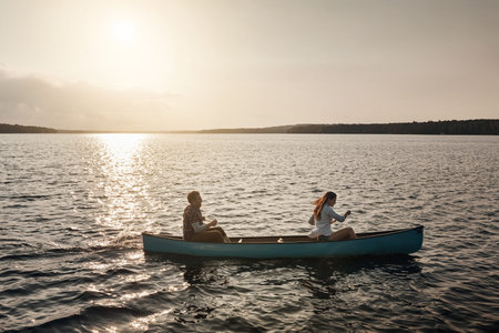 Couple, canoe and sunset on lake for holiday, adventure and outdoor weekend. Travel, space and man...